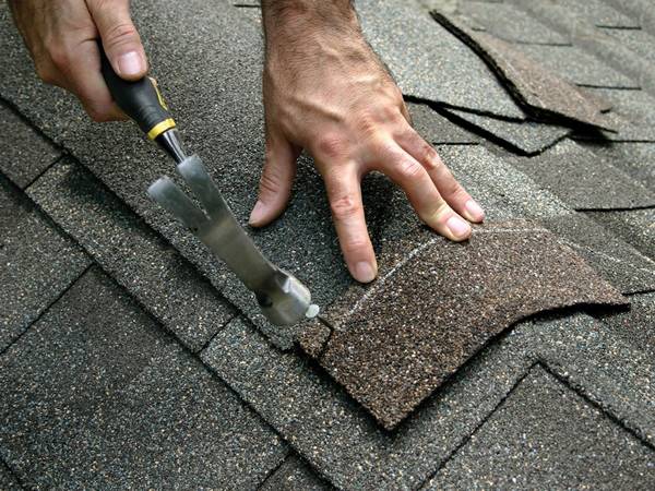 A man is installing the ridge cap shingle with clout nail.