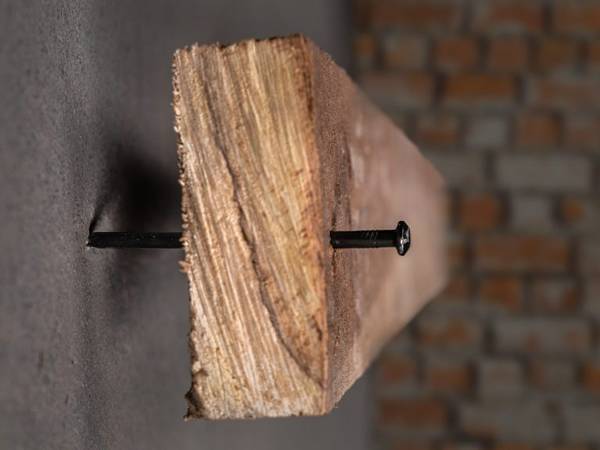 Prenda a laje de madeira na parede de concreto com prego de concreto preto.
